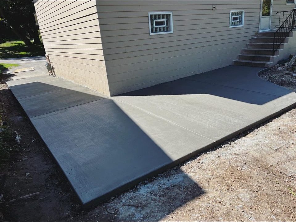 Concrete apron and side approach poured alongside a home with entry steps and railing