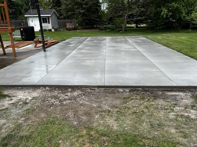 Large broom-finish concrete pad freshly poured in a backyard