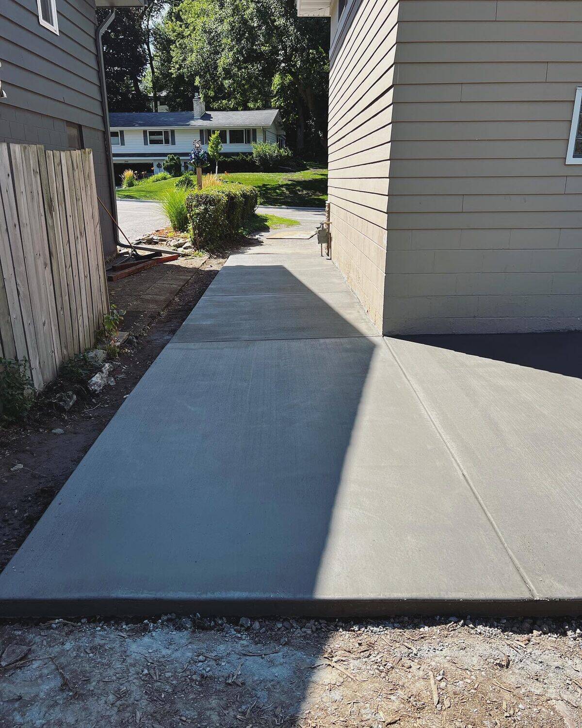 New broom-finish concrete side walkway running between the house and fence to the driveway