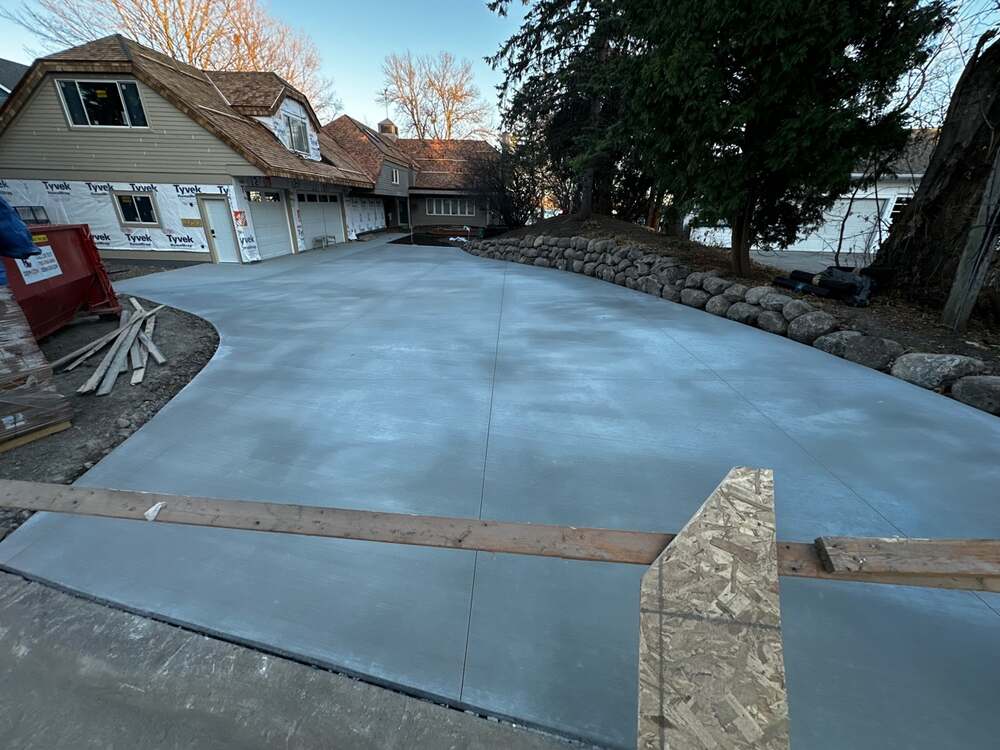 New construction concrete driveway with curved edge and boulder wall in Elk River, MN