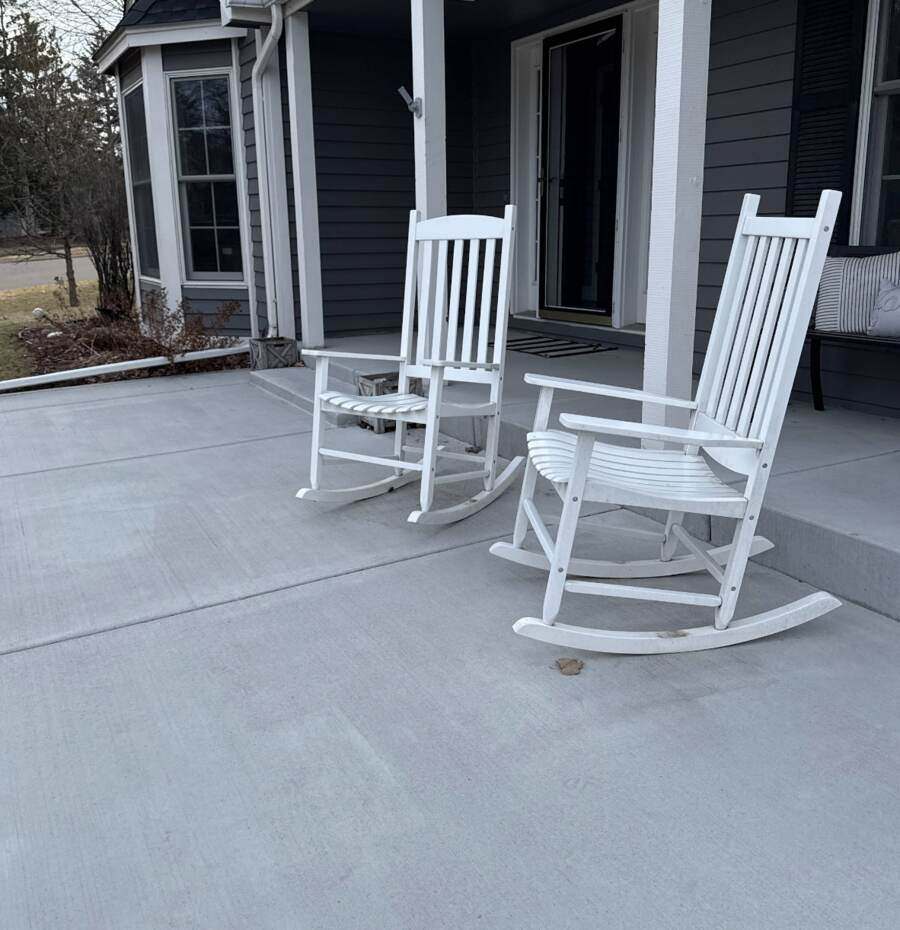 Finished concrete front porch with steps, furnished with rocking chairs